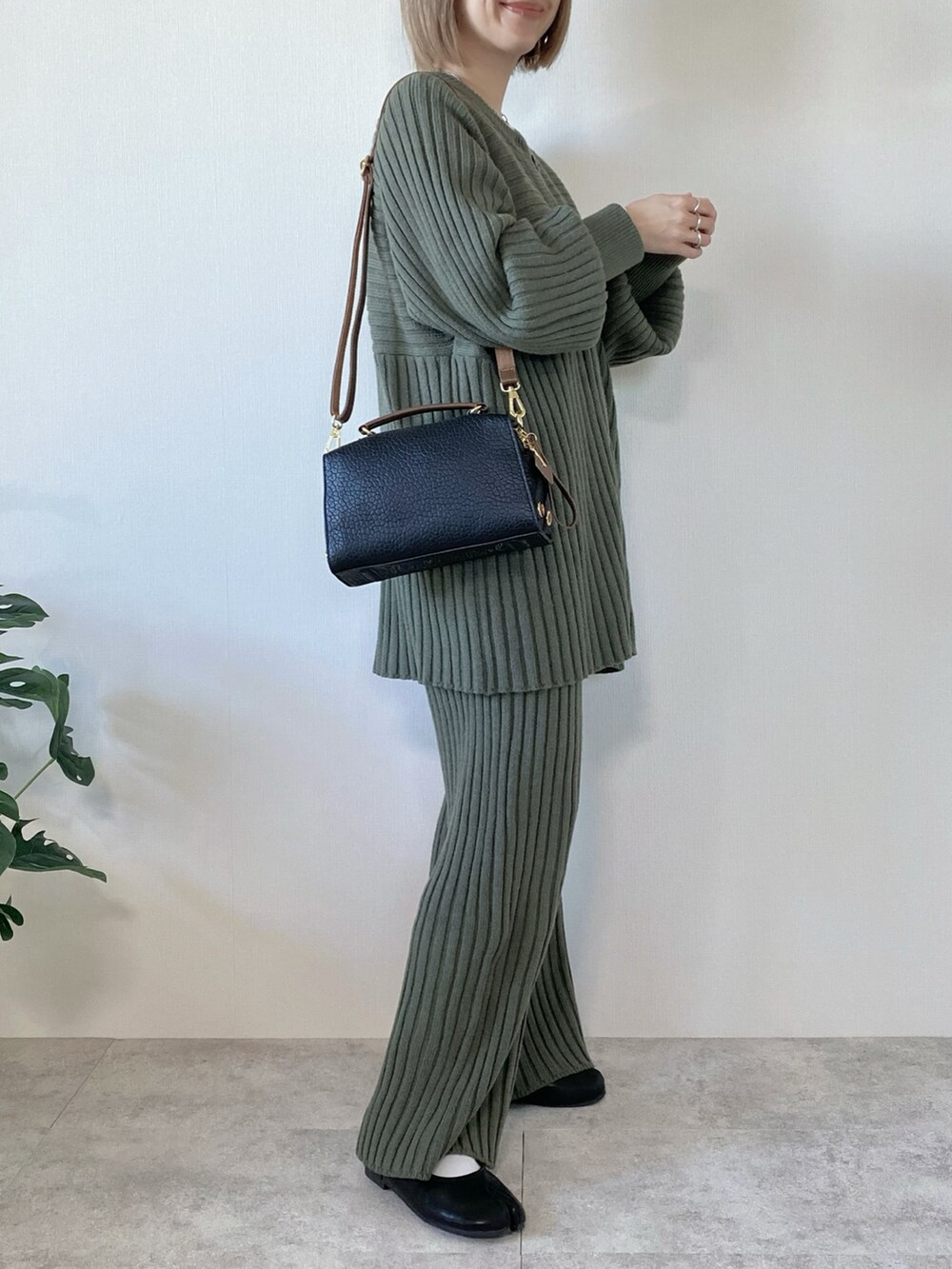 ブラック系のボストンバッグ、グリーン系のニット/セーター、ブラック系のパンプスを着用したレディースの冬コーディネートの2枚目の写真
