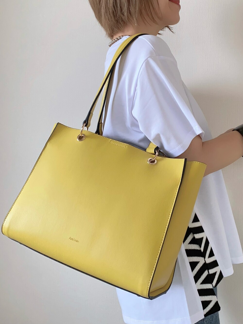 イエロー系のトートバッグ、ホワイト系のトップス、シルバー系のサンダルを着用したレディースの夏コーディネートの4枚目の写真