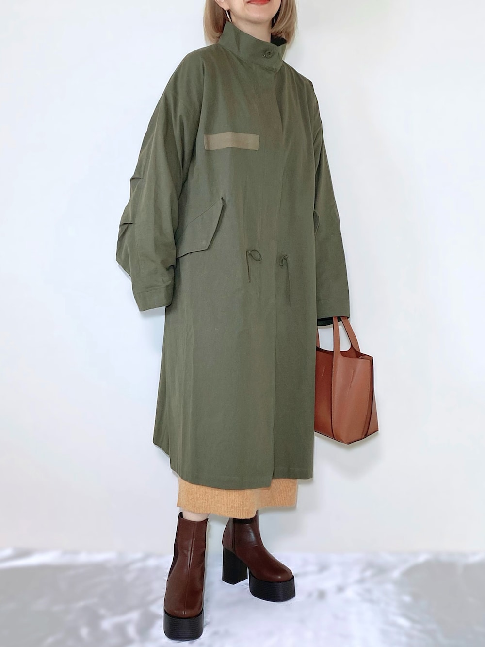 オレンジ系のワンピース、ブラウン系のバッグ、ブラウン系のブーツを着用したレディースの秋コーディネートの3枚目の写真