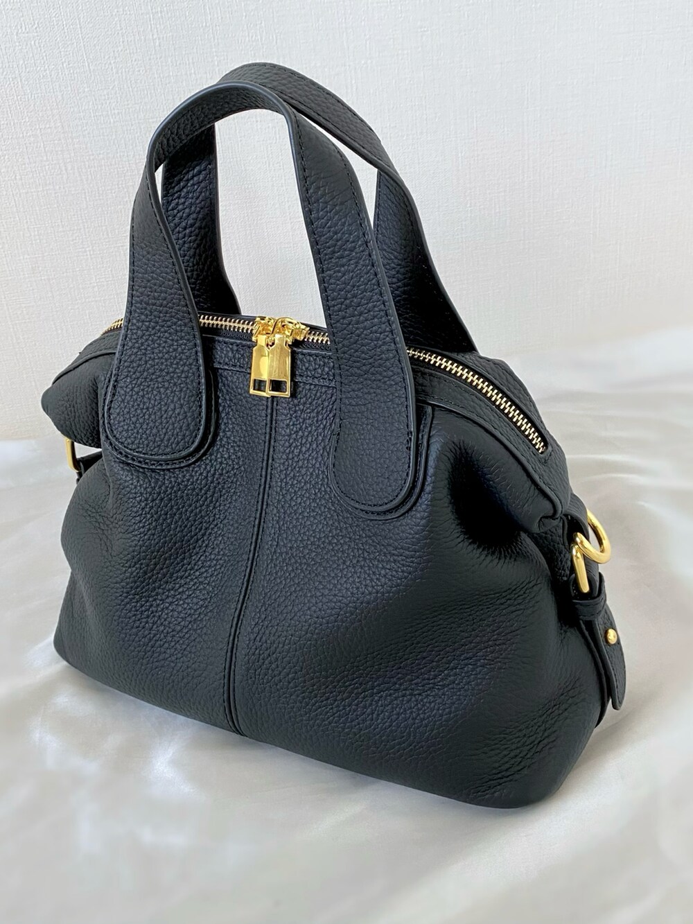 ブラック系のバッグ、ブルー系のベスト、ホワイト系のサンダルを着用したレディースの夏コーディネートの4枚目の写真