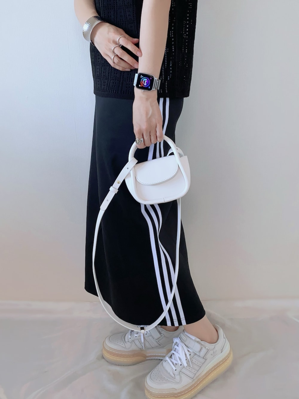ブラック系のスカート、ホワイト系のショルダーバッグ、ブラック系のニット/セーターを着用したレディースの夏コーディネートの3枚目の写真