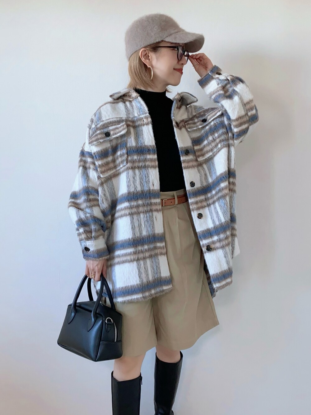 ホワイト系のブルゾン、ブラック系のニット/セーター、ブラック系のバッグを着用したレディースの秋コーディネートの2枚目の写真