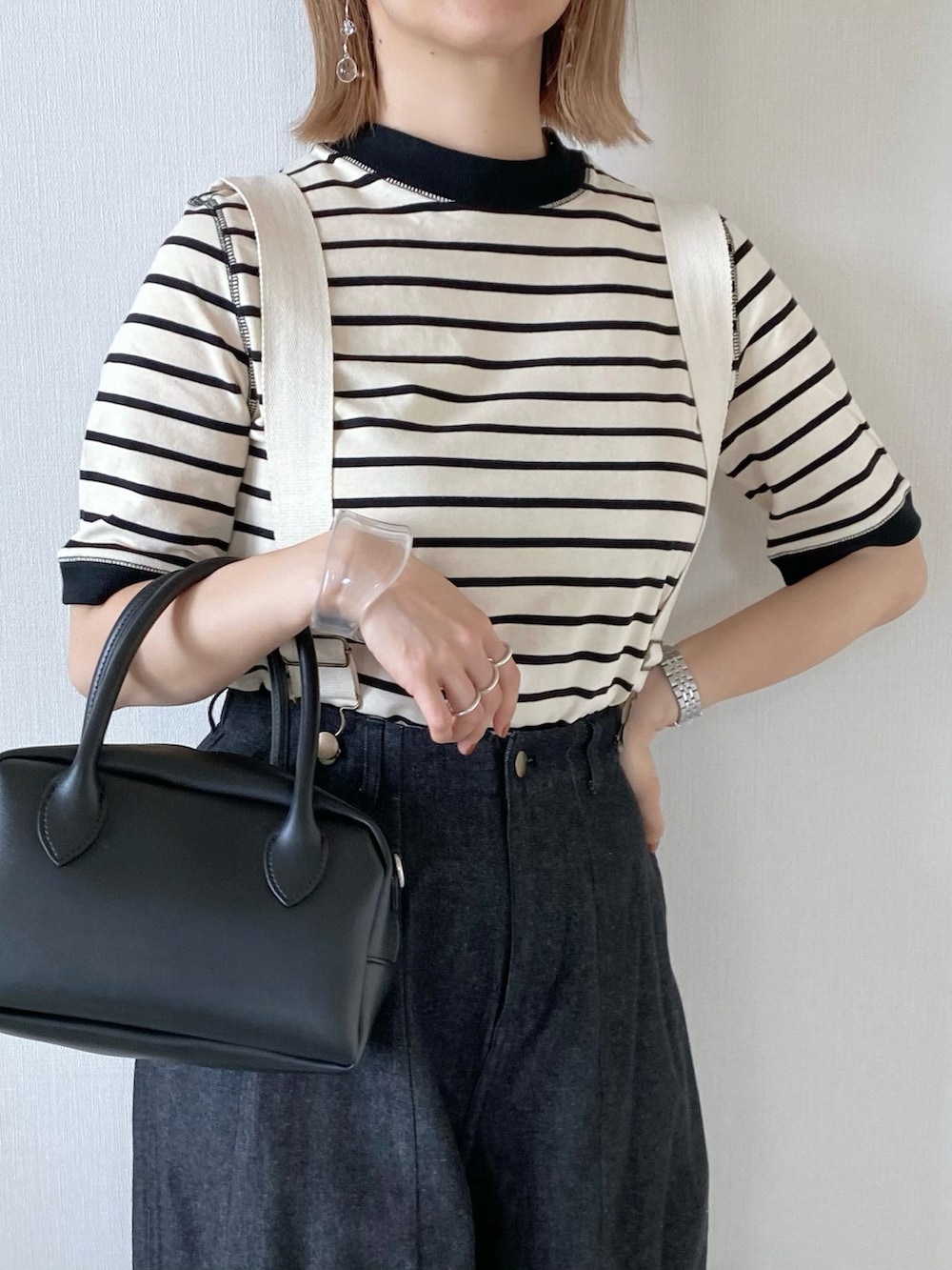 ブラック系のデニムパンツ、ブラック系のバッグ、ベージュ系のサンダルを着用したレディースの春コーディネートの3枚目の写真