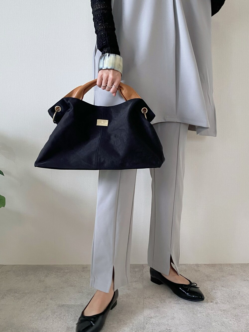 ブラック系のトートバッグ、グレー系のアンサンブル、グレー系のその他パンツを着用したレディースの春コーディネートの4枚目の写真