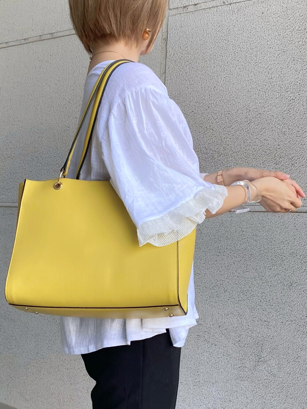 イエロー系のトートバッグ、ホワイト系のシャツ/ブラウス、ブラック系のパンツを着用したレディースの夏コーディネートの5枚目の写真