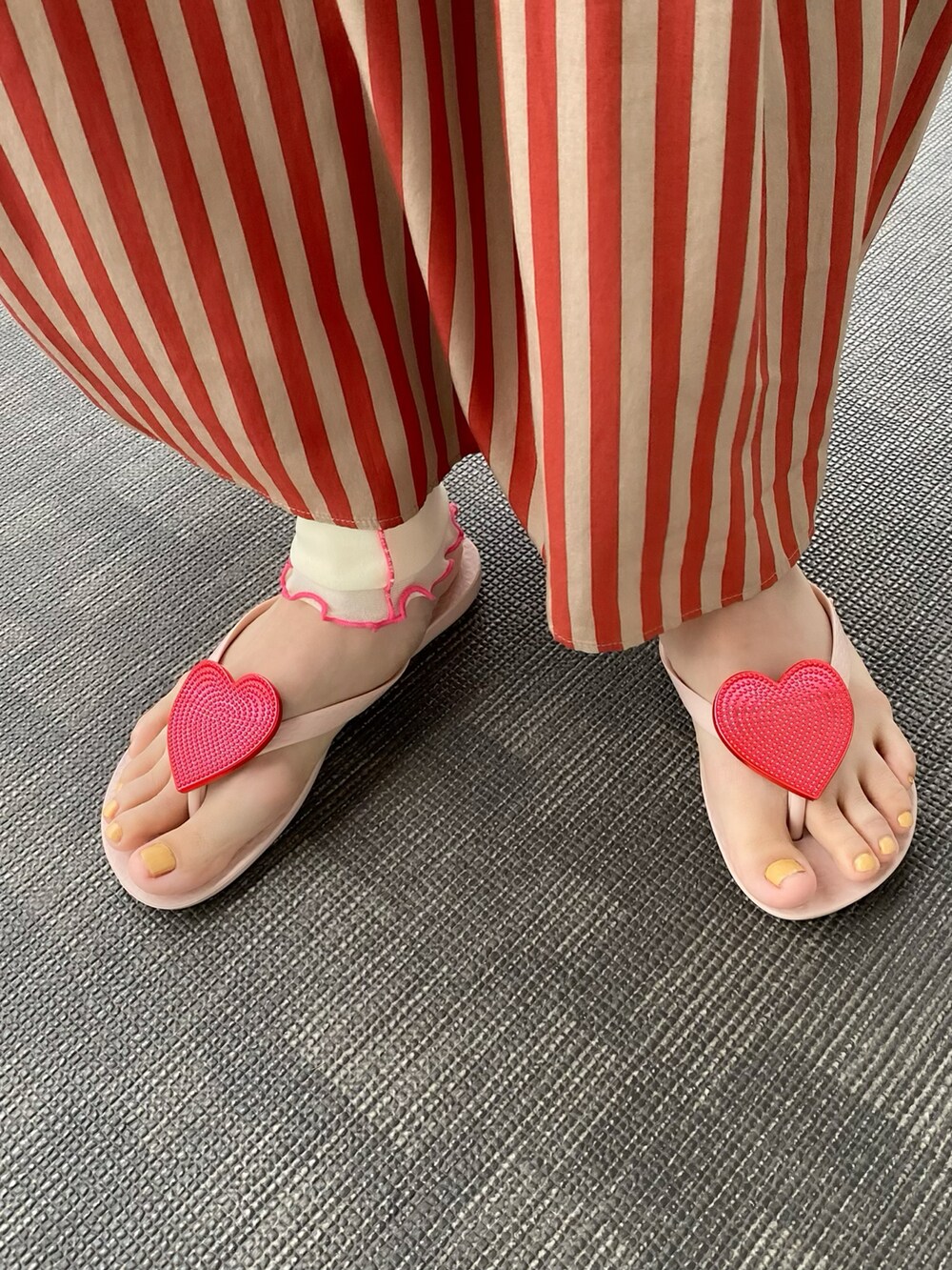 ベージュ系のワンピース、オレンジ系のバッグ、ピンク系のサンダルを着用したレディースの夏コーディネートの2枚目の写真