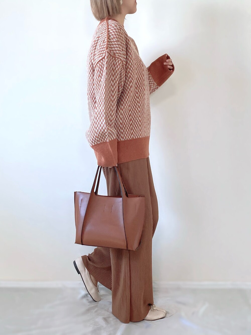 オレンジ系のニット/セーター、ブラウン系のバッグ、ホワイト系のバレエシューズを着用したレディースの秋コーディネートの2枚目の写真