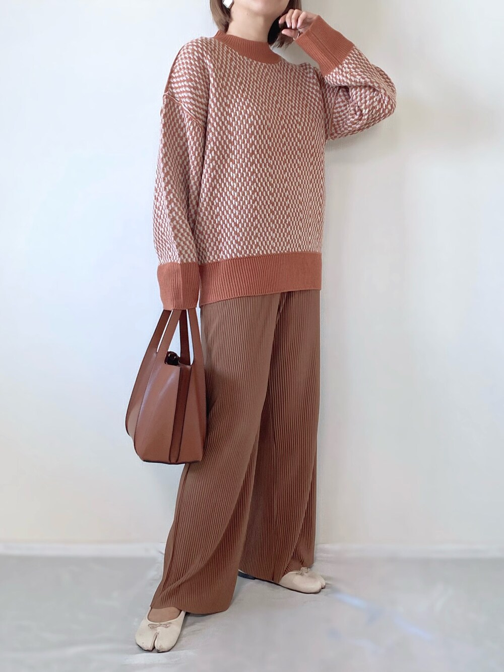 オレンジ系のニット/セーター、ブラウン系のバッグ、ホワイト系のバレエシューズを着用したレディースの秋コーディネートの3枚目の写真