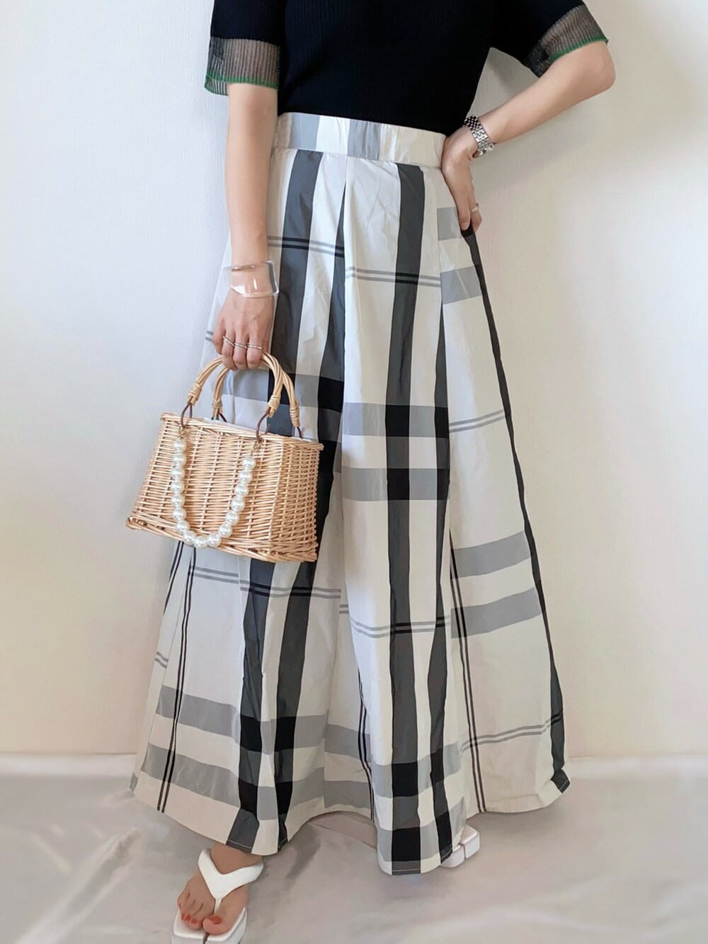 ブラック系のニット/セーター、ホワイト系のスカート、ベージュ系のかごバッグを着用したレディースの夏コーディネートの4枚目の写真