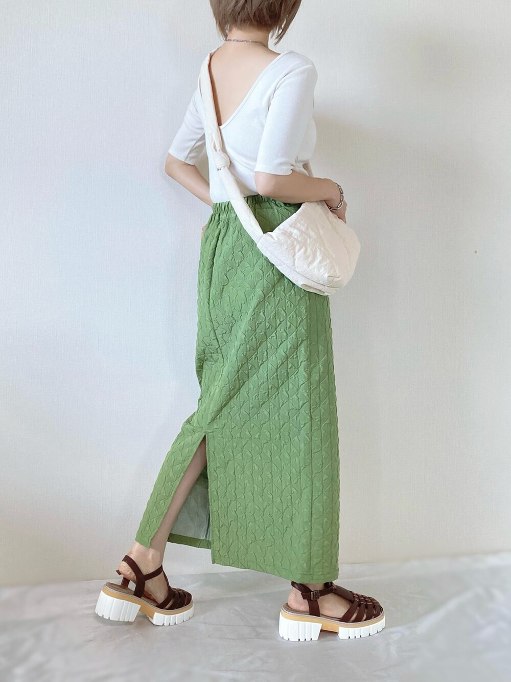 グリーン系のスカート、ホワイト系のTシャツ/カットソー、ホワイト系のショルダーバッグを着用したレディースの夏コーディネートの2枚目の写真