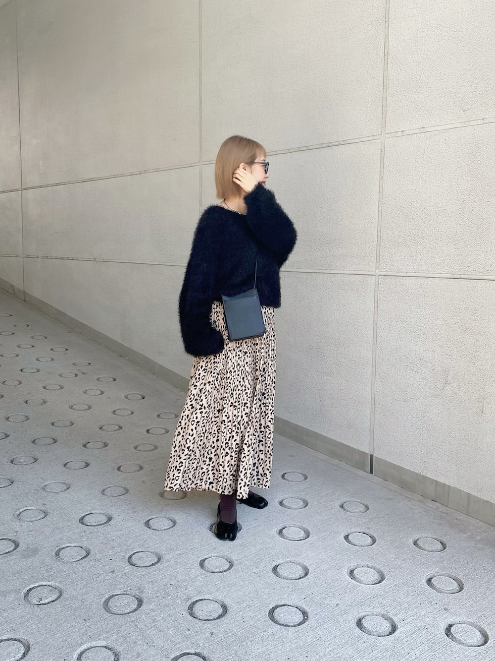 ブラック系のニット/セーター、ブラック系のショルダーバッグ、ベージュ系のスカートを着用したレディースの秋コーディネートの3枚目の写真