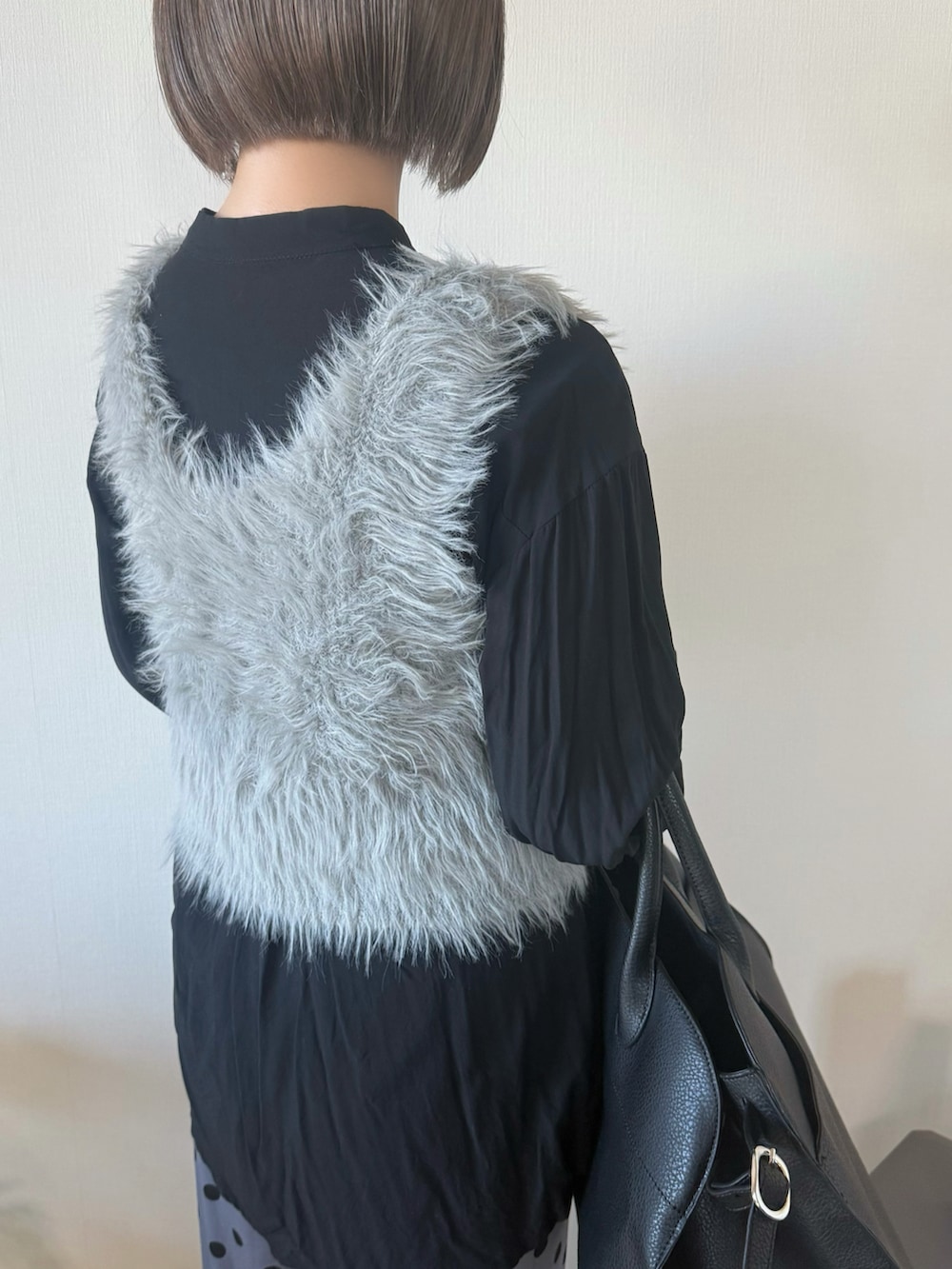 ベージュ系のベスト、ブラック系のボストンバッグ、グレー系のパンツを着用したレディースの冬コーディネートの5枚目の写真