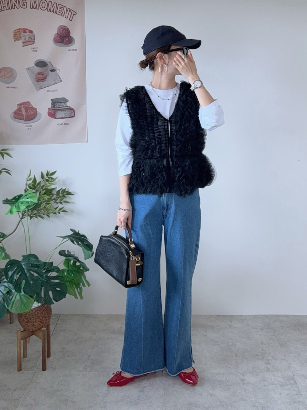 ブラック系のベスト、ブルー系のデニムパンツ、レッド系のバレエシューズを着用したレディースの秋コーディネートの2枚目の写真