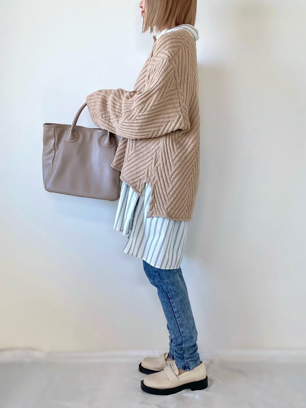 ベージュ系のニット/セーター、ホワイト系のシャツ/ブラウス、ベージュ系のバッグを着用したレディースの冬コーディネートの2枚目の写真