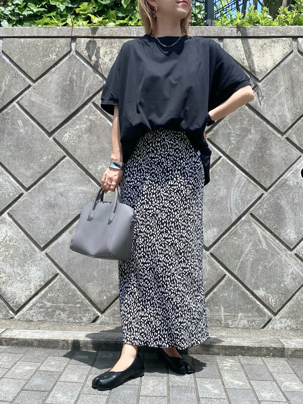 ブラック系のスカート、ブラック系のパンプス、グレー系のハンドバッグを着用したレディースの夏コーディネートの3枚目の写真