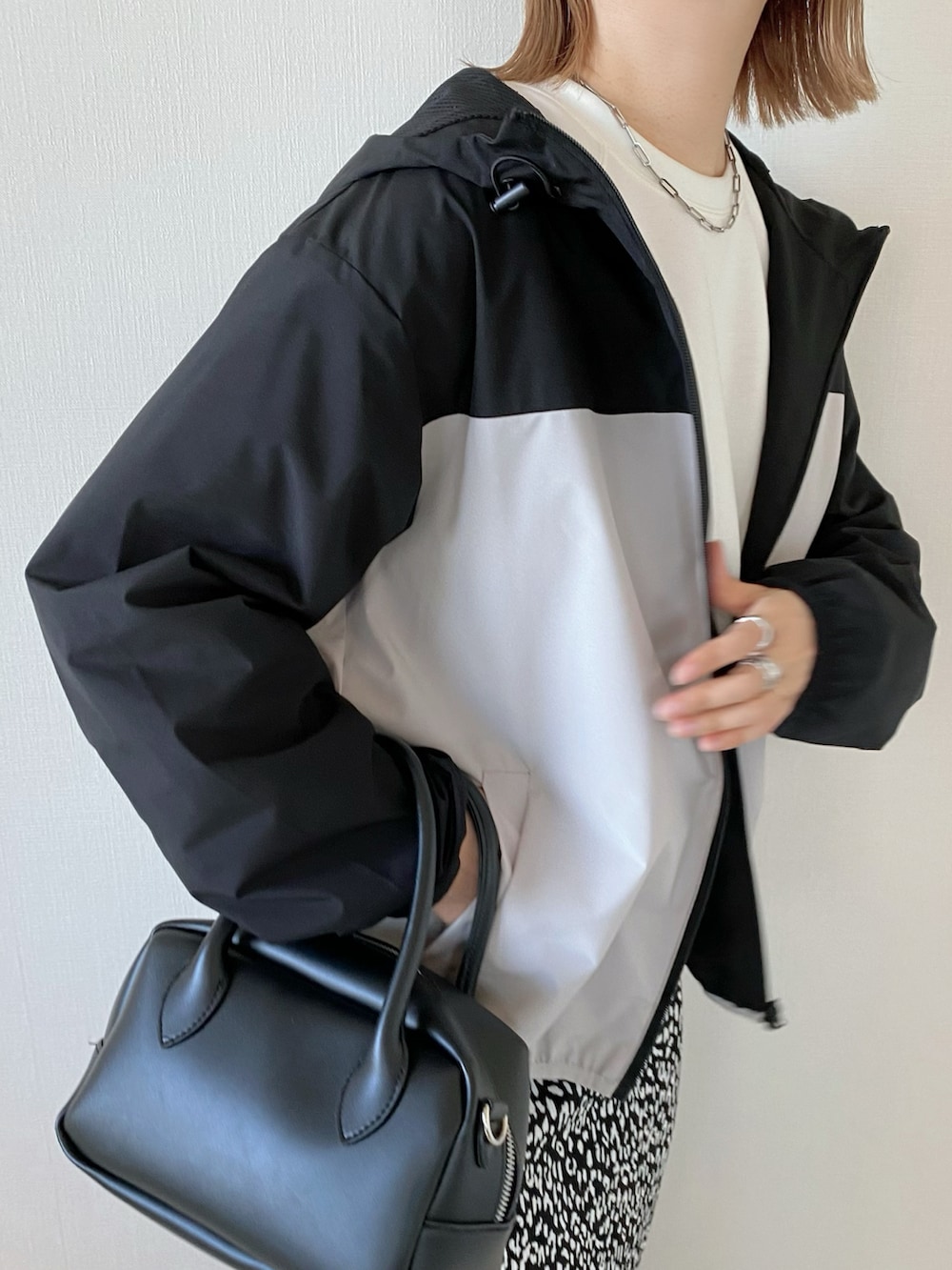 ブラック系のバッグ、ブラック系のスカート、ベージュ系のマウンテンパーカーを着用したレディースの春コーディネートの4枚目の写真