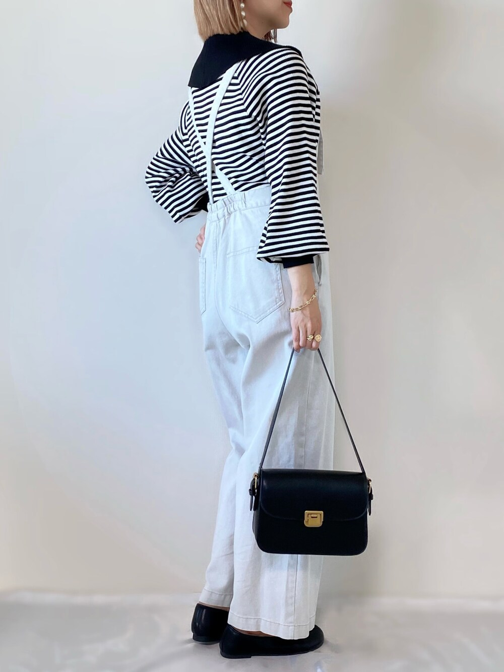 ブラック系のショルダーバッグ、ブラック系のニット/セーター、ホワイト系のサロペット/オーバーオールを着用したレディースの冬コーディネートの3枚目の写真