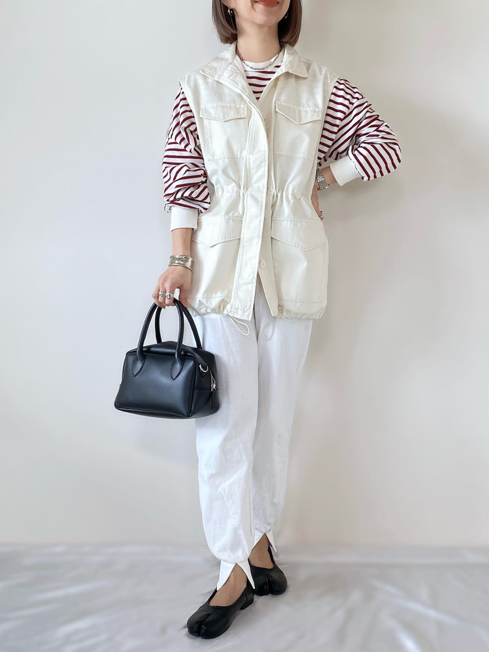 レッド系のTシャツ/カットソー、ホワイト系のベスト、ホワイト系のその他パンツを着用したレディースの冬コーディネートの4枚目の写真