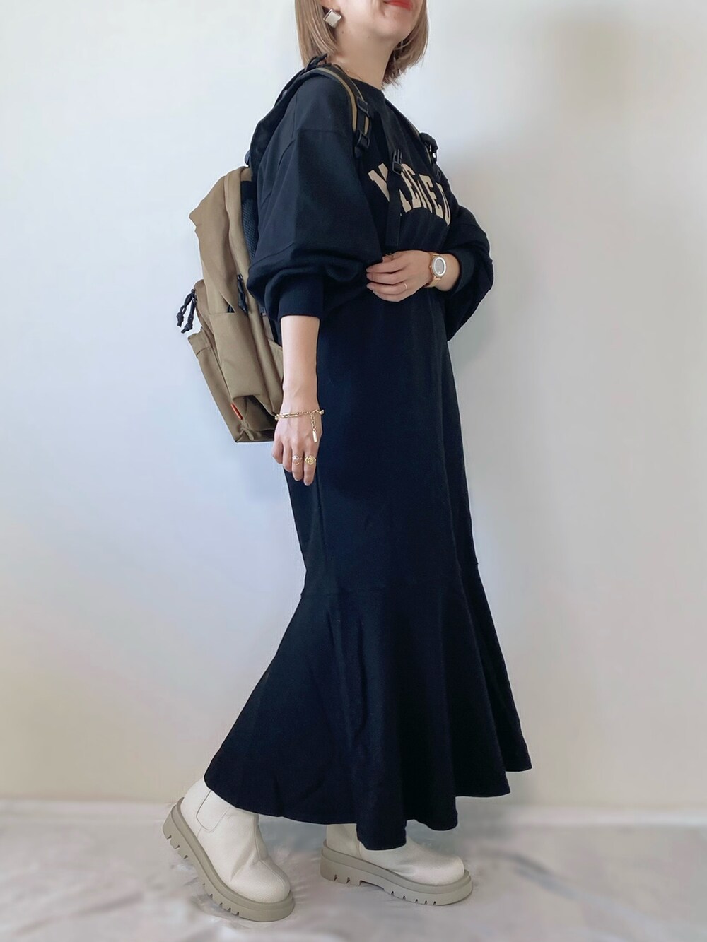 ホワイト系のブーツ、ブラック系のワンピース、ベージュ系のバックパック/リュックを着用したレディースの秋コーディネートの2枚目の写真