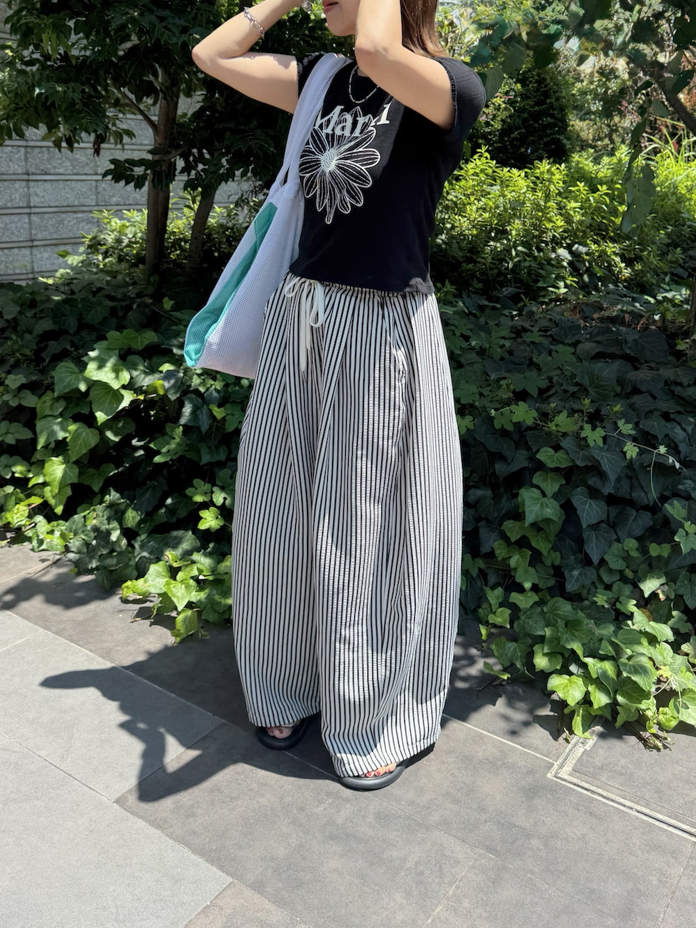 ホワイト系のその他パンツ、ブラック系のTシャツ/カットソー、ホワイト系のトートバッグを着用したレディースの夏コーディネートの2枚目の写真
