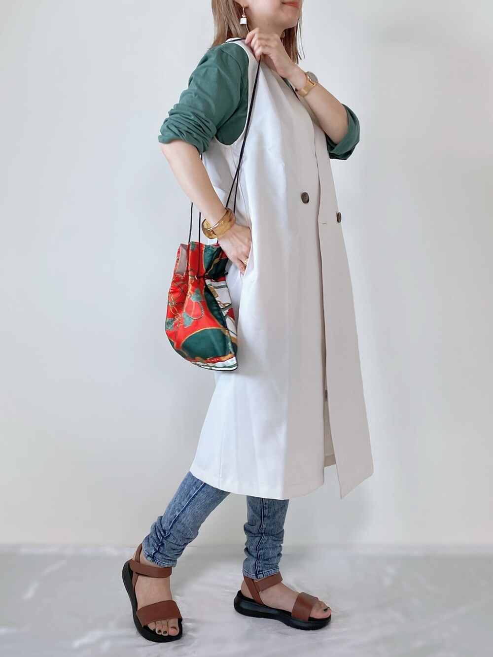 ブラウン系のサンダル、ホワイト系のベスト、その他のバッグを着用したレディースの春コーディネートの2枚目の写真