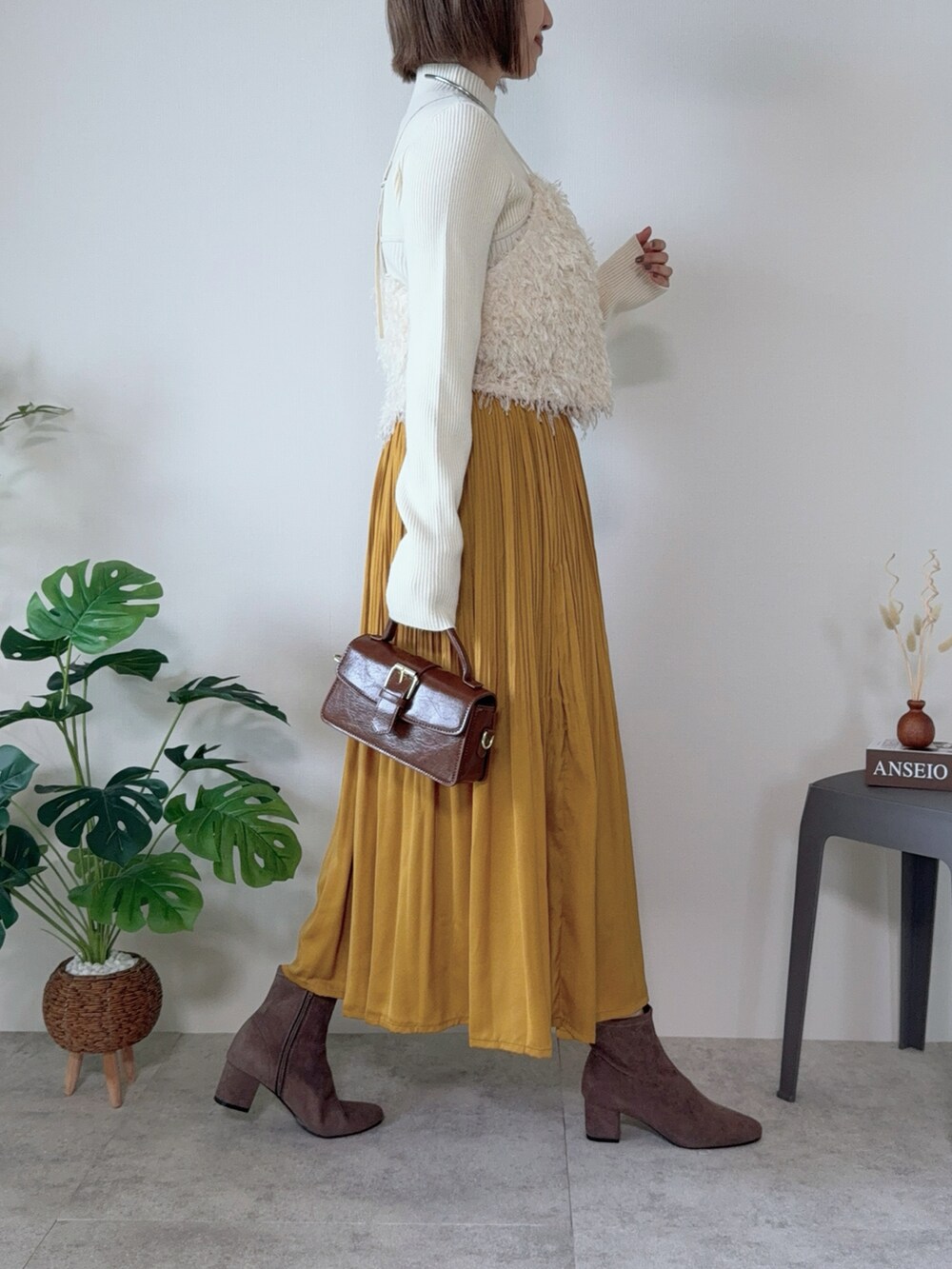 イエロー系のスカート、ブラウン系のハンドバッグ、ホワイト系のシャツ/ブラウスを着用したレディースの秋コーディネートの2枚目の写真