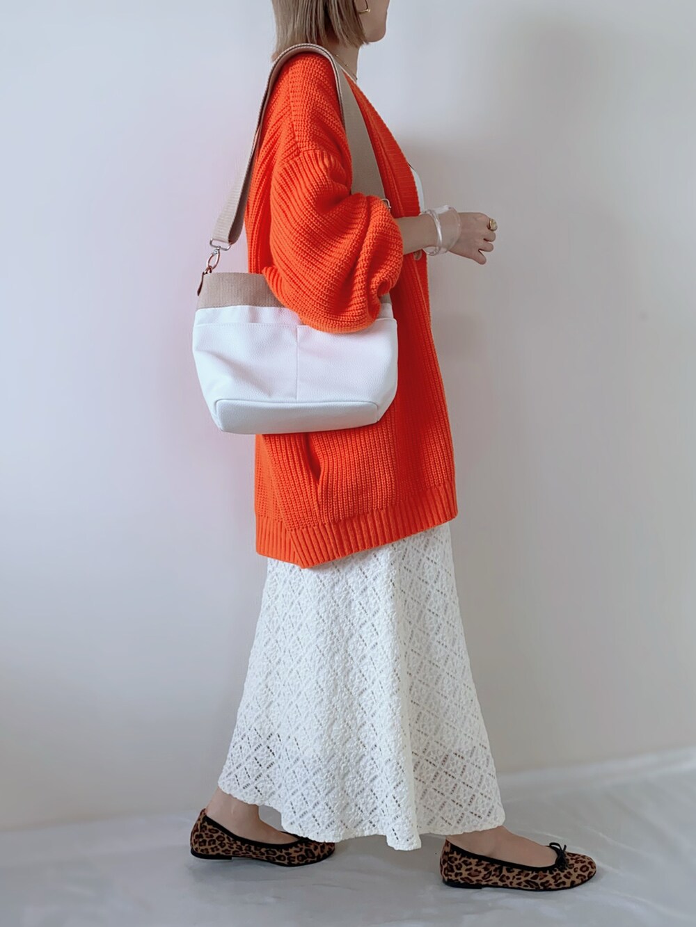 ホワイト系のTシャツ/カットソー、オレンジ系のカーディガン/ボレロ、ホワイト系のスカートを着用したレディースの春コーディネートの2枚目の写真