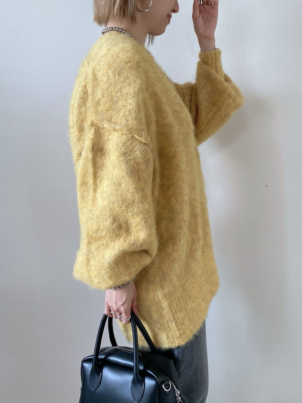 イエロー系のカーディガン/ボレロ、ブラック系のバッグ、グレー系のデニムパンツを着用したレディースの冬コーディネートの4枚目の写真