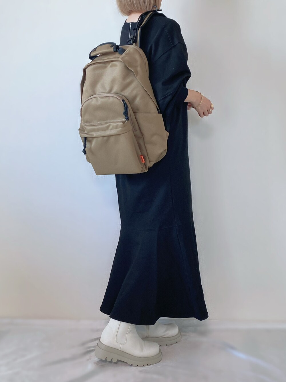 ホワイト系のブーツ、ブラック系のワンピース、ベージュ系のバックパック/リュックを着用したレディースの秋コーディネートの3枚目の写真