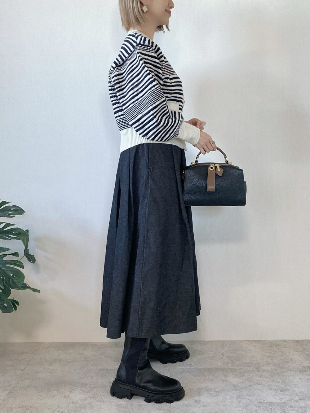 ブラック系のボストンバッグ、ホワイト系のカーディガン/ボレロ、ブラック系のスカートを着用したレディースの冬コーディネートの2枚目の写真