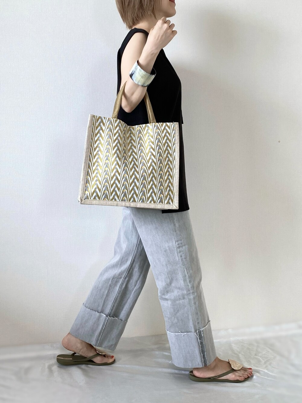 イエロー系のかごバッグ、グレー系のデニムパンツ、グリーン系のサンダルを着用したレディースの夏コーディネートの2枚目の写真