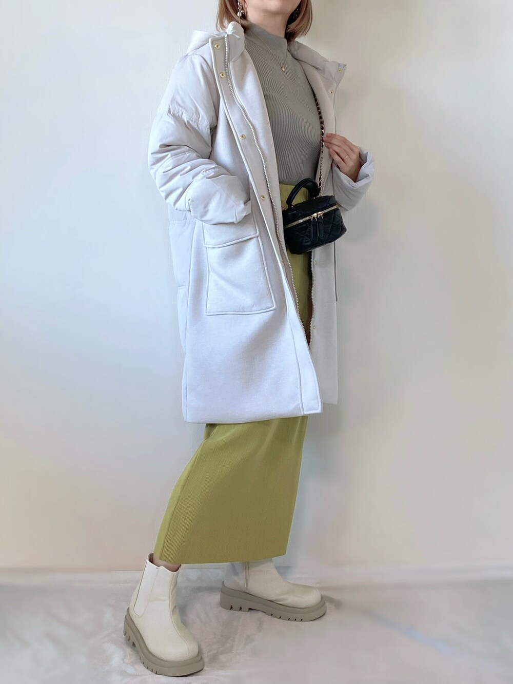 グレー系のダウンジャケット/コート、グレー系のニット/セーター、グリーン系のスカートを着用したレディースの冬コーディネートの3枚目の写真