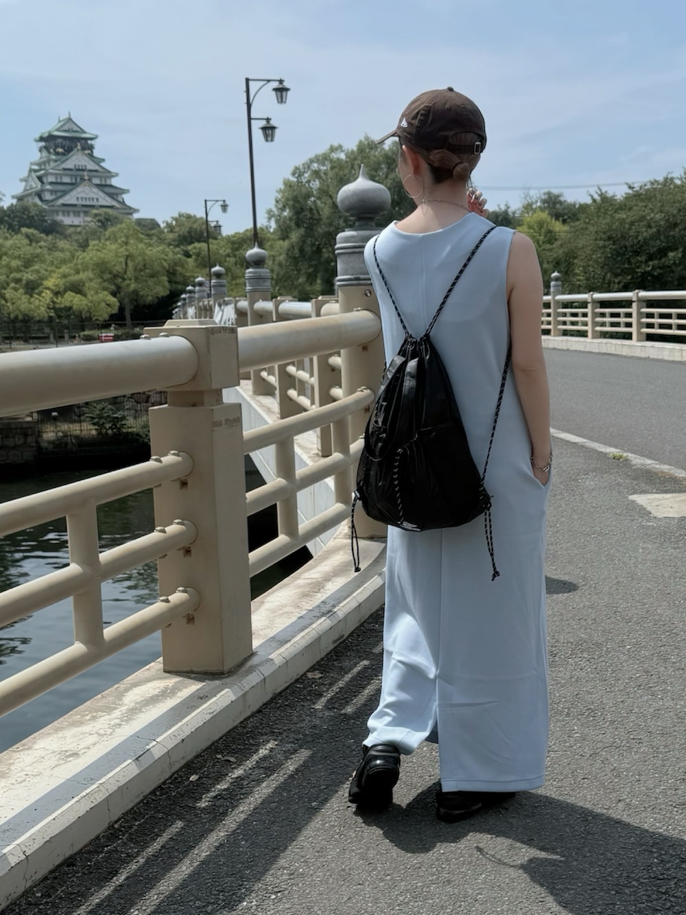 ブラック系のサンダル、ブルー系のジャンパースカート、ブラウン系のキャップを着用したレディースの秋コーディネートの2枚目の写真