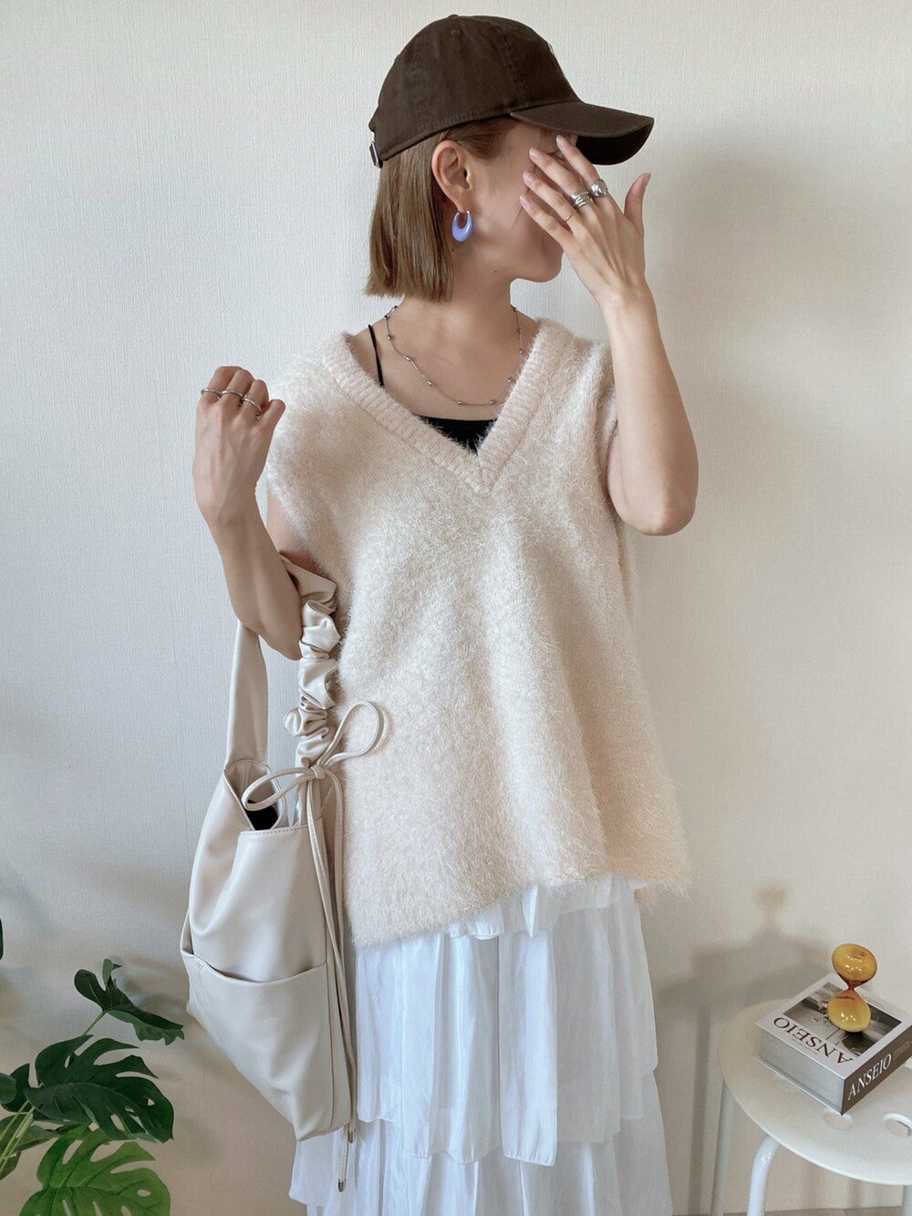 ホワイト系のベスト、ゴールド系のスニーカー、ホワイト系のスカートを着用したレディースの秋コーディネートの5枚目の写真