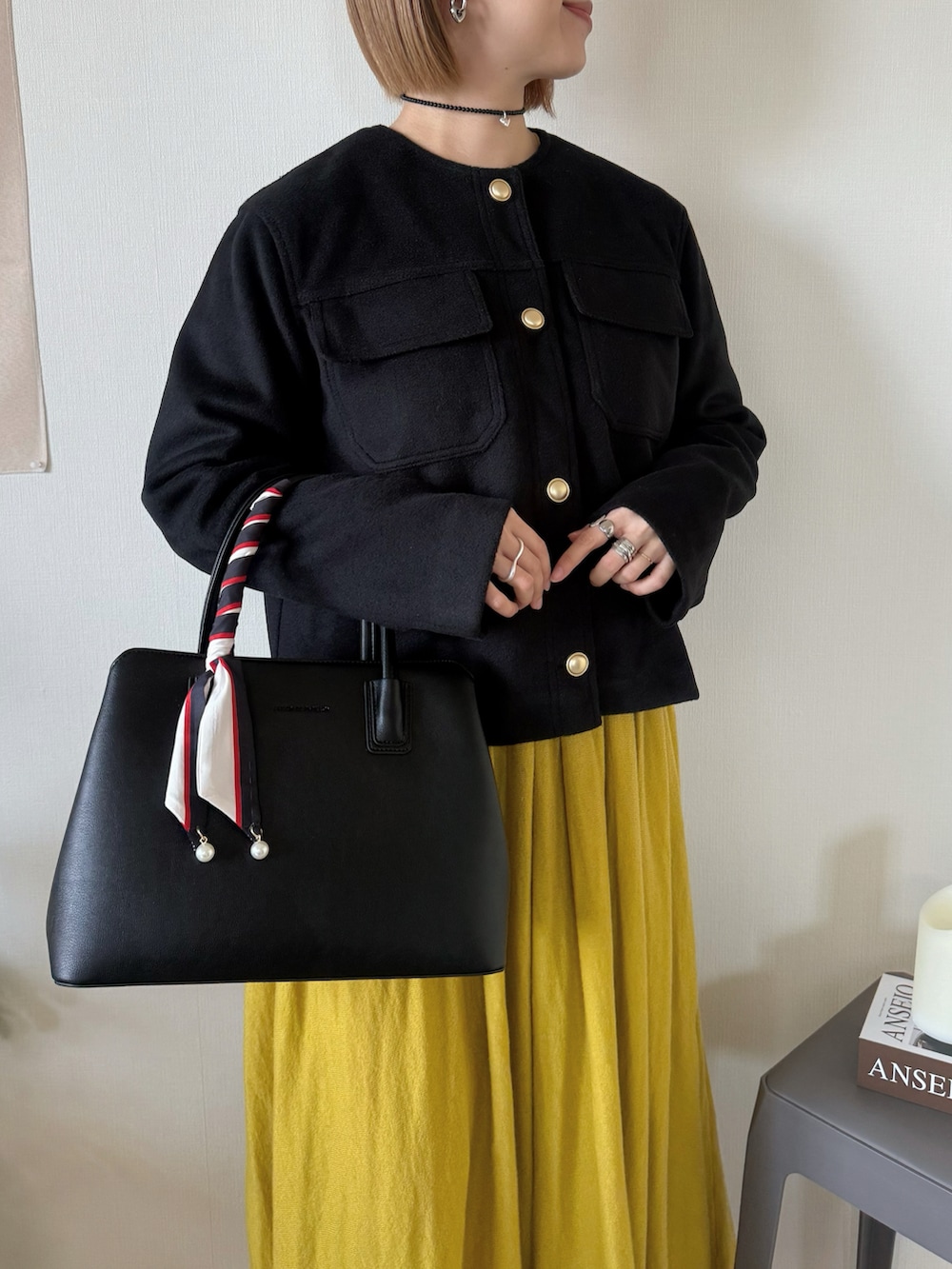 ブラック系のジャケット/アウター、ブラック系のハンドバッグ、イエロー系のワンピースを着用したレディースの冬コーディネートの2枚目の写真