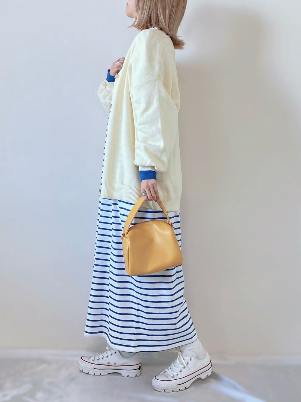 イエロー系のバッグ、ブルー系のワンピース、ホワイト系のスニーカーを着用したレディースの春コーディネートの3枚目の写真