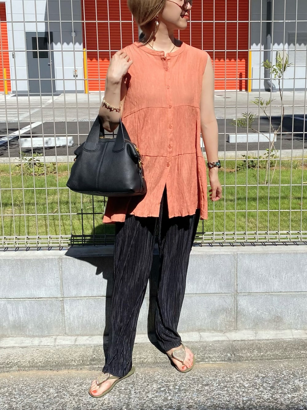 オレンジ系のシャツ/ブラウス、ブラック系のバッグ、ブラック系のその他パンツを着用したレディースの夏コーディネートの4枚目の写真