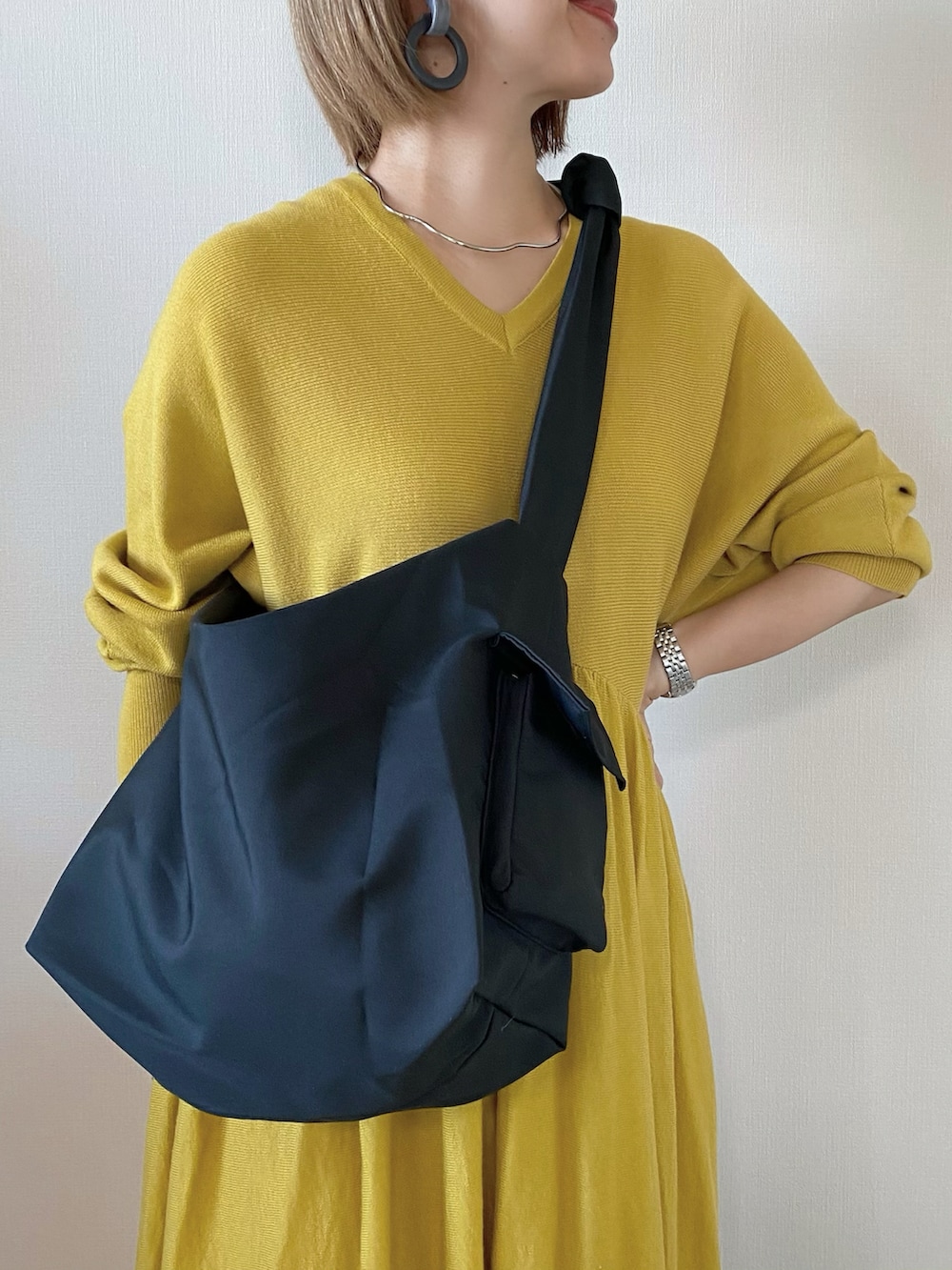 ブラック系のメッセンジャーバッグ、イエロー系のワンピース、ブラック系のスリッポンを着用したレディースの冬コーディネートの5枚目の写真