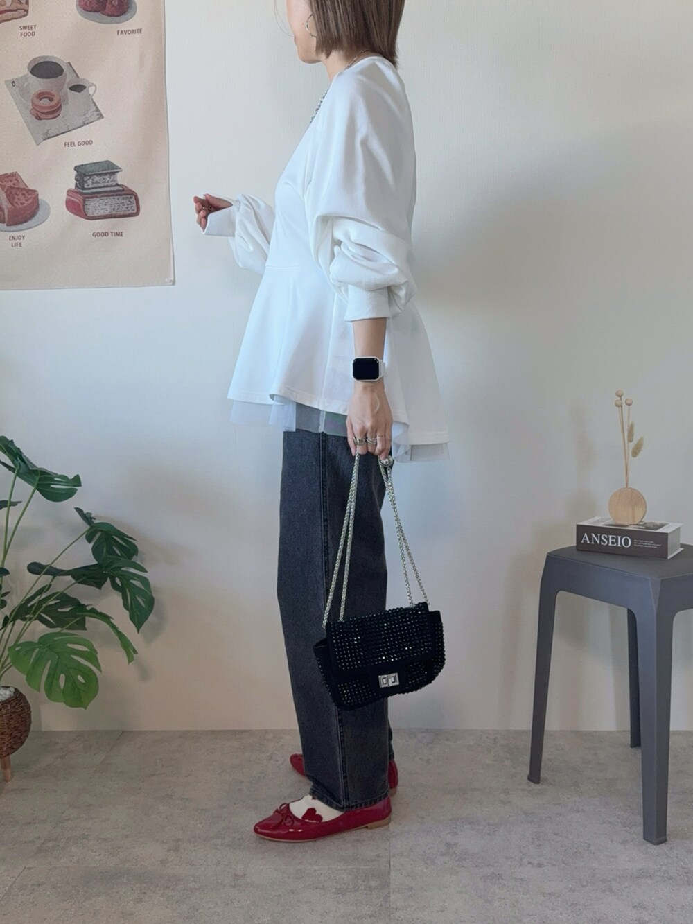 ホワイト系のスウェット、ブラック系のデニムパンツ、ブラック系のクラッチバッグを着用したレディースの冬コーディネートの2枚目の写真