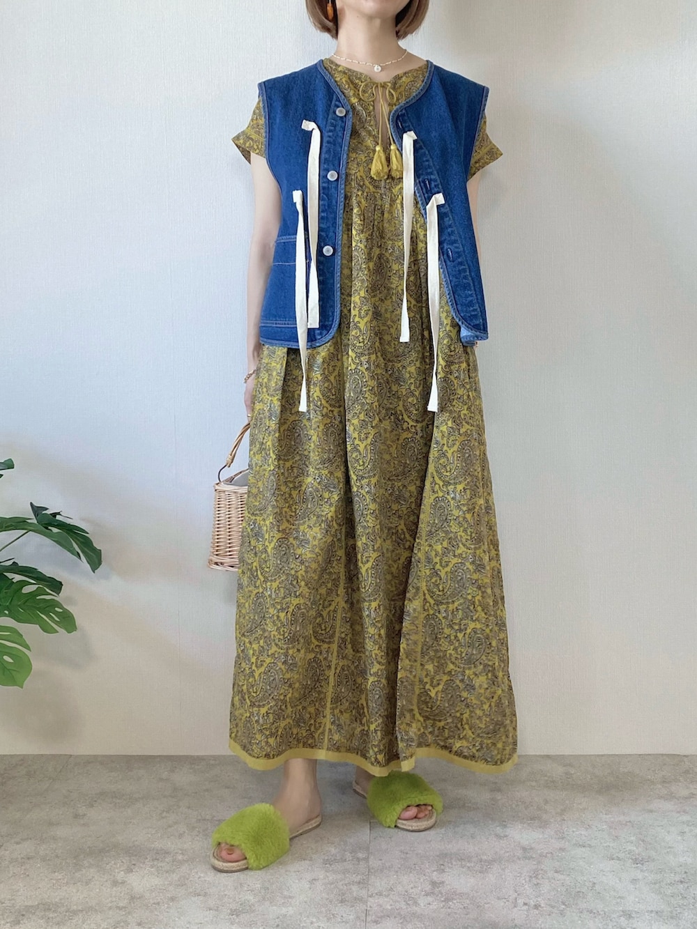 ベージュ系のかごバッグ、イエロー系のワンピース、ブルー系のベストを着用したレディースの春コーディネートの2枚目の写真