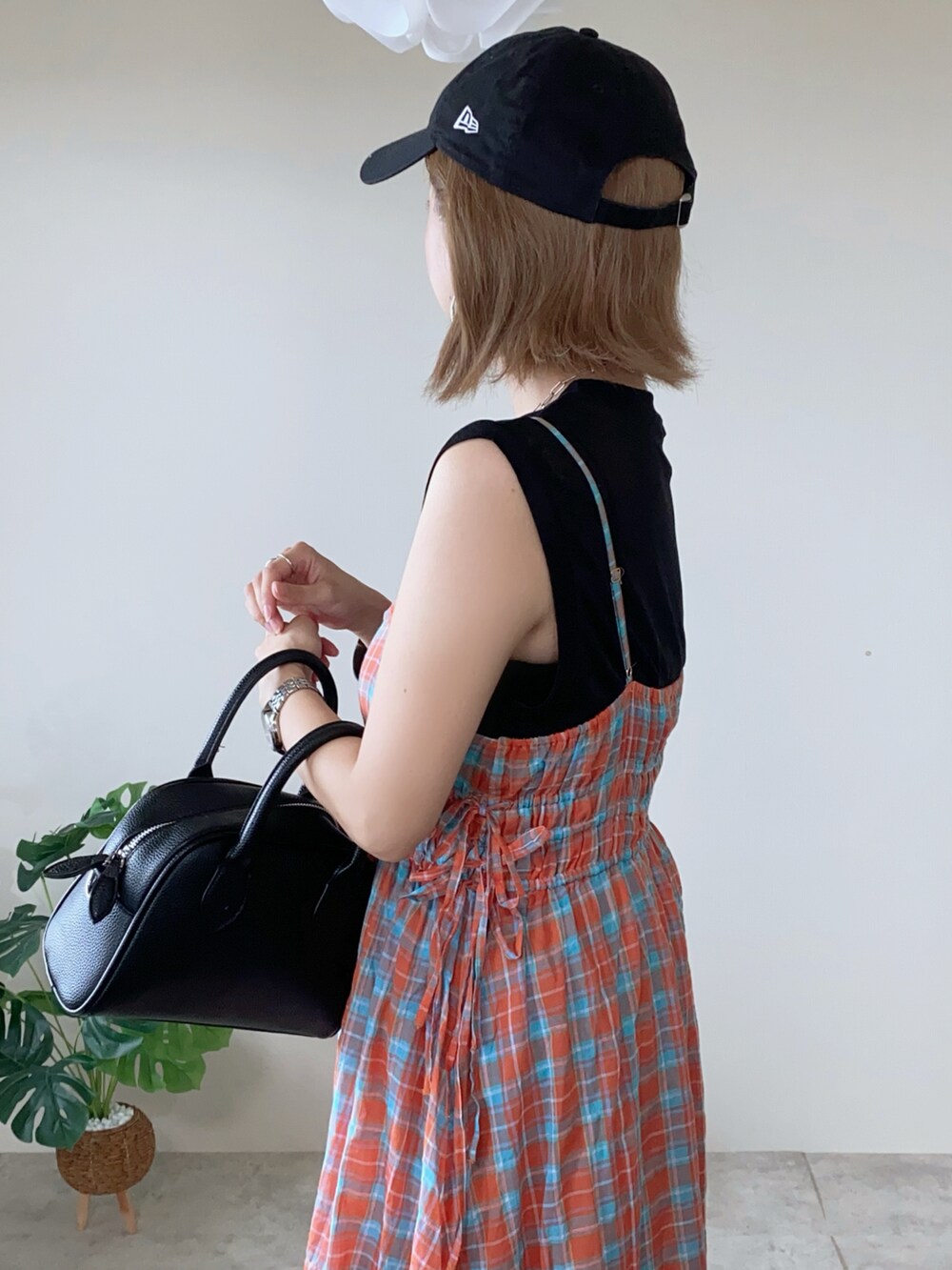 ホワイト系のスニーカー、オレンジ系のワンピース、ブラック系のボストンバッグを着用したレディースの夏コーディネートの5枚目の写真