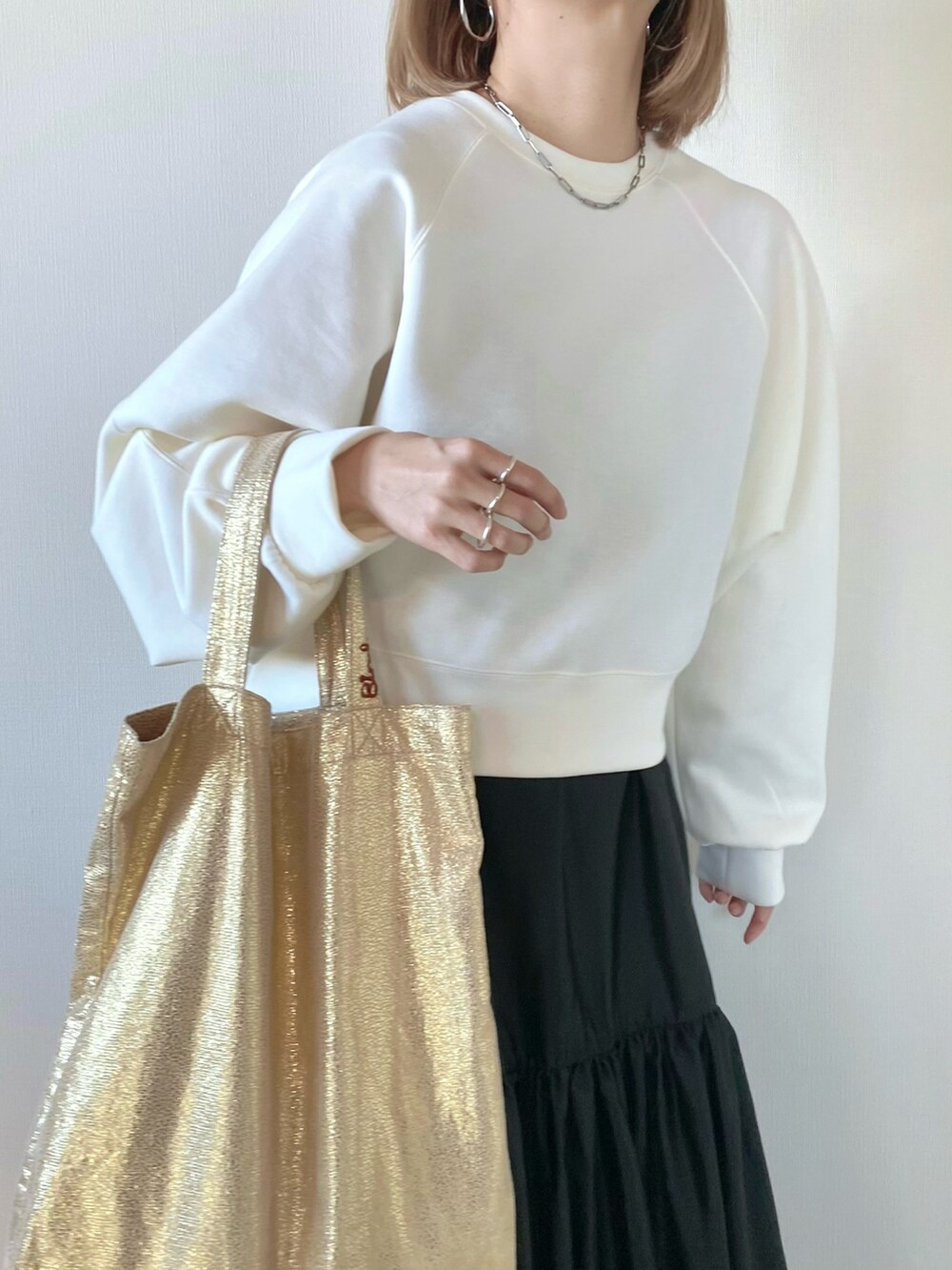 ホワイト系のスウェット、ゴールド系のトートバッグ、グレー系のワンピースを着用したレディースの冬コーディネートの4枚目の写真