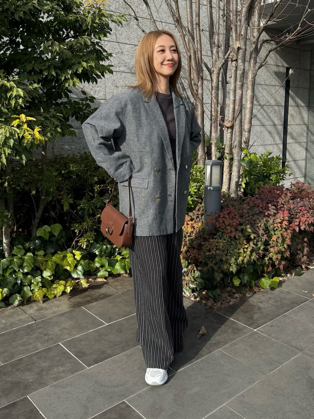 ブラック系のテーラードジャケット、ブラウン系のハンドバッグ、ブラック系のその他パンツを着用したレディースの冬コーディネートの2枚目の写真