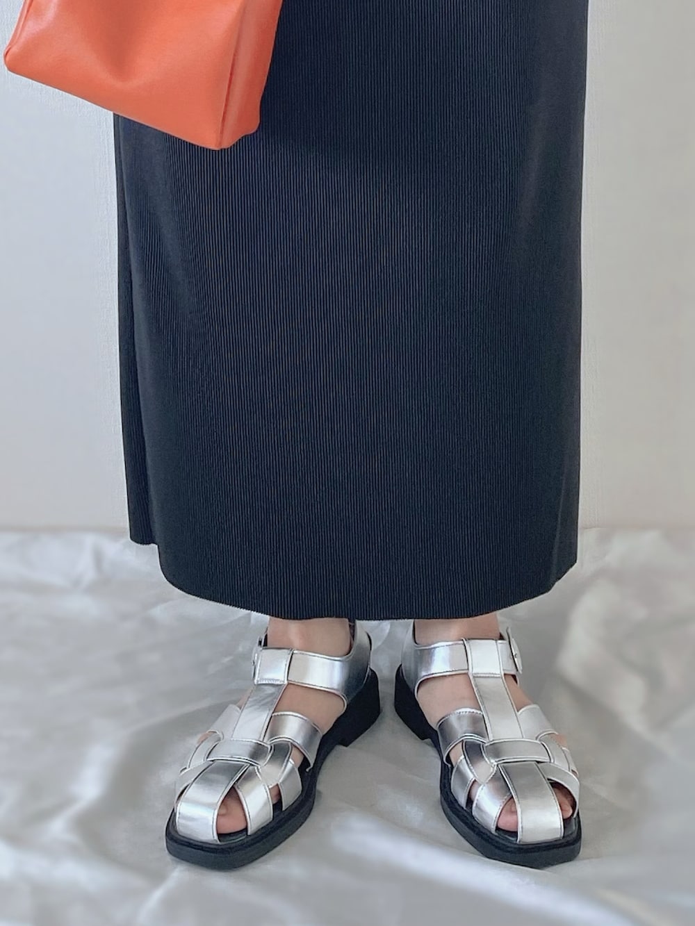 シルバー系のサンダル、オレンジ系のバッグ、ブラック系のスカートを着用したレディースの春コーディネートの4枚目の写真