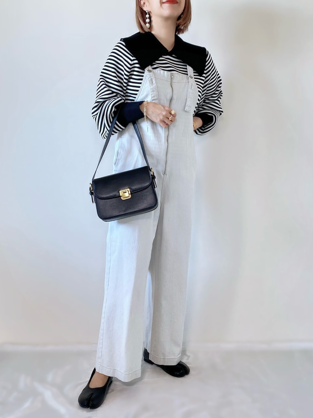 ブラック系のショルダーバッグ、ブラック系のニット/セーター、ホワイト系のサロペット/オーバーオールを着用したレディースの冬コーディネートの2枚目の写真