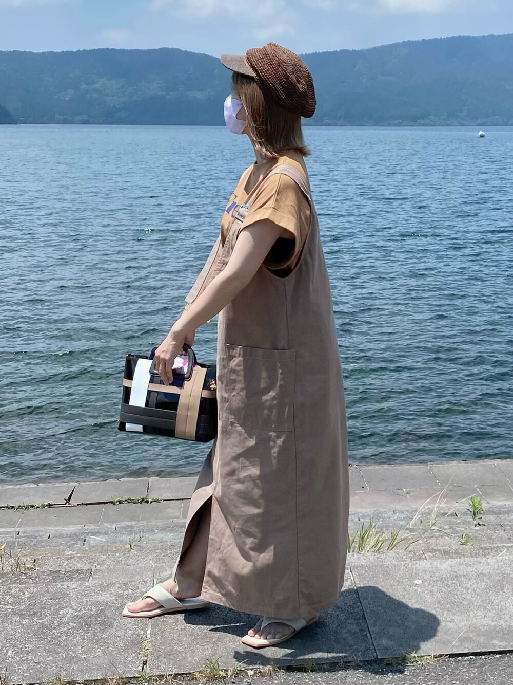 ブラウン系のTシャツ/カットソー、ベージュ系のジャンパースカート、ホワイト系のサンダルを着用したレディースの夏コーディネートの2枚目の写真