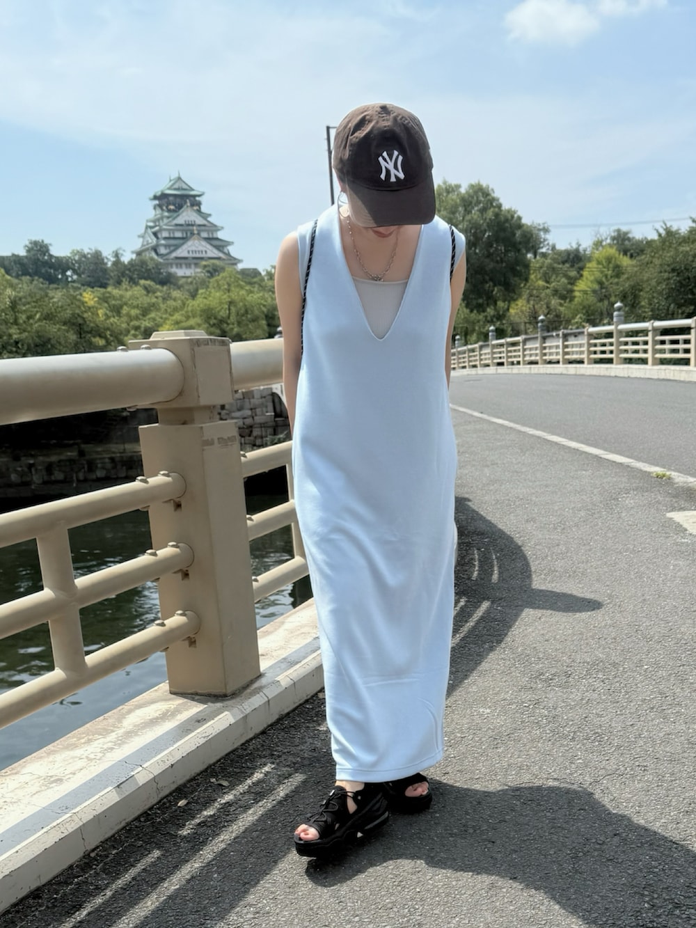 ブラック系のサンダル、ブルー系のジャンパースカート、ブラウン系のキャップを着用したレディースの秋コーディネートの3枚目の写真