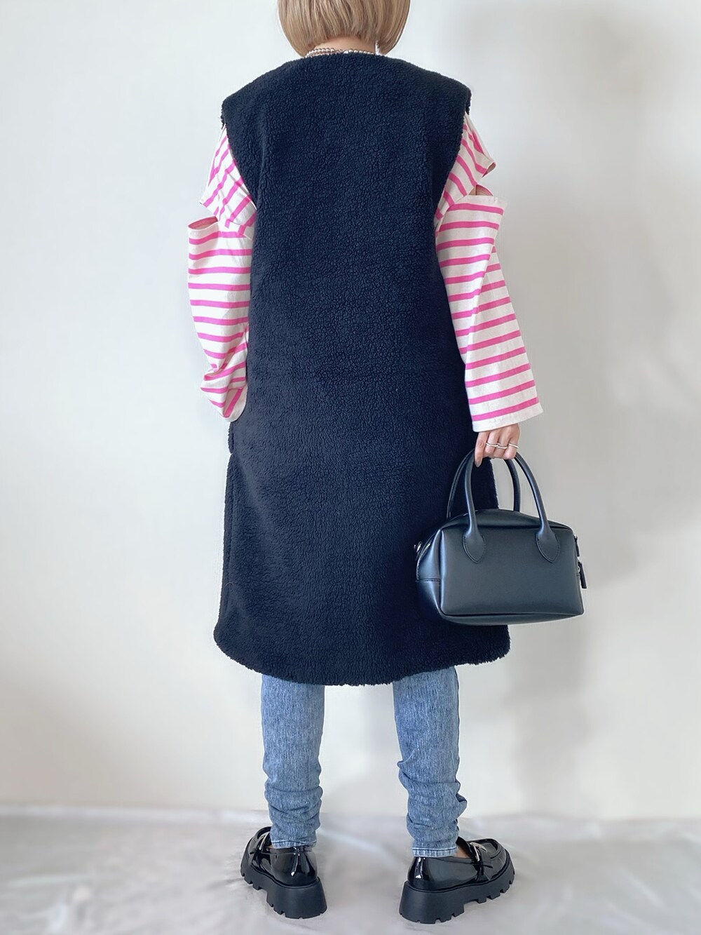 ブラック系のベスト、ピンク系のTシャツ/カットソー、ブラック系のバッグを着用したレディースの秋コーディネートの3枚目の写真