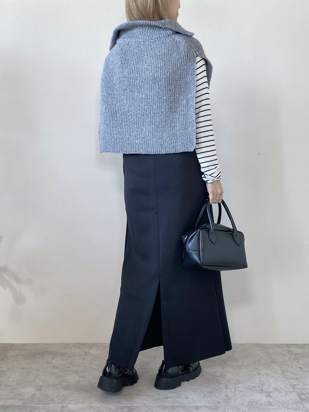 グレー系のベスト、ホワイト系のTシャツ/カットソー、ブラック系のスカートを着用したレディースの冬コーディネートの3枚目の写真