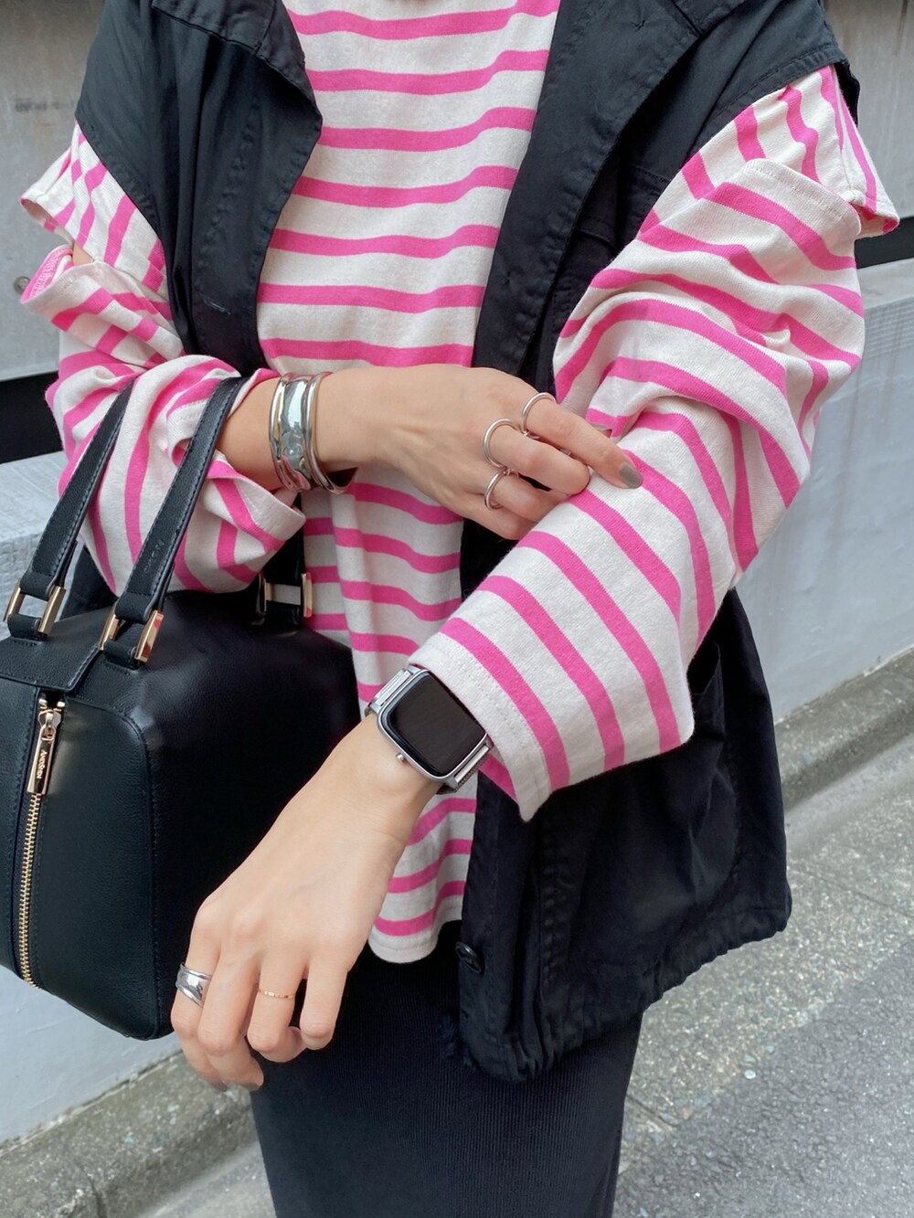 ブラック系のベスト、ピンク系のTシャツ/カットソー、ブラック系のハンドバッグを着用したレディースの秋コーディネートの3枚目の写真